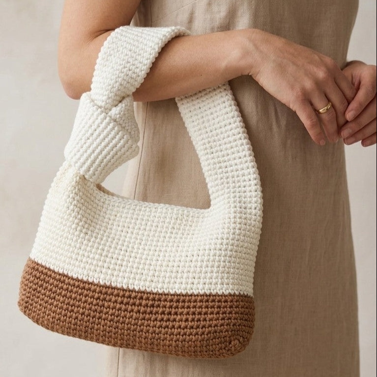 Digital PDF crochet pattern for a modern knotted handbag. Make a stylish crochet bag with a two-tone body, sturdy handle and knot detail. US terms.