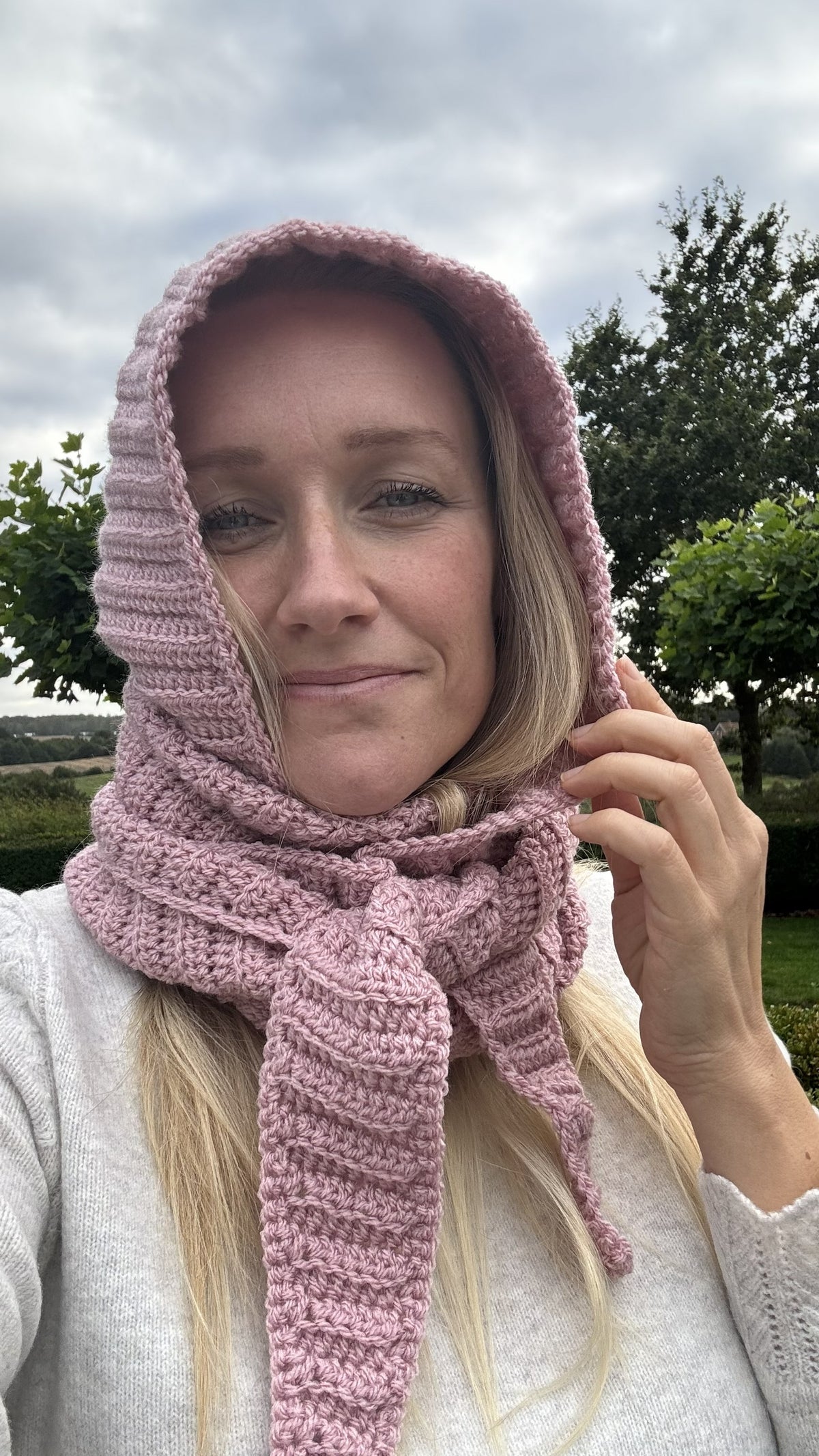 Front detail of a pink ribbed Sophie Hood worn with the crochet scarf wrapped around the neck