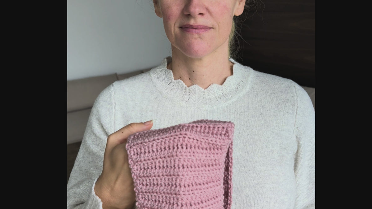 Woman wearing a dusty pink ribbed Sophie Scarf tied around her neck over a cream sweater, with two tapered crochet ends hanging in front.