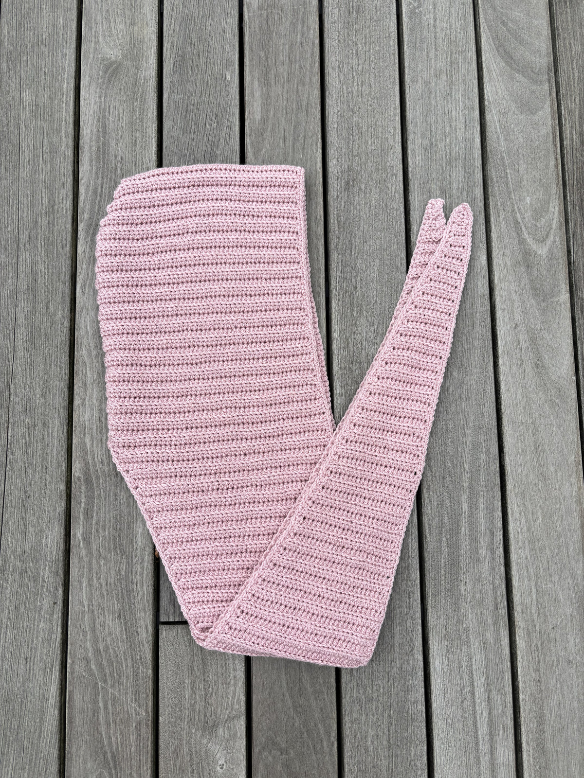 Pink ribbed Sophie Hood crochet piece laid flat showing the shaped hood and tapered scarf ends