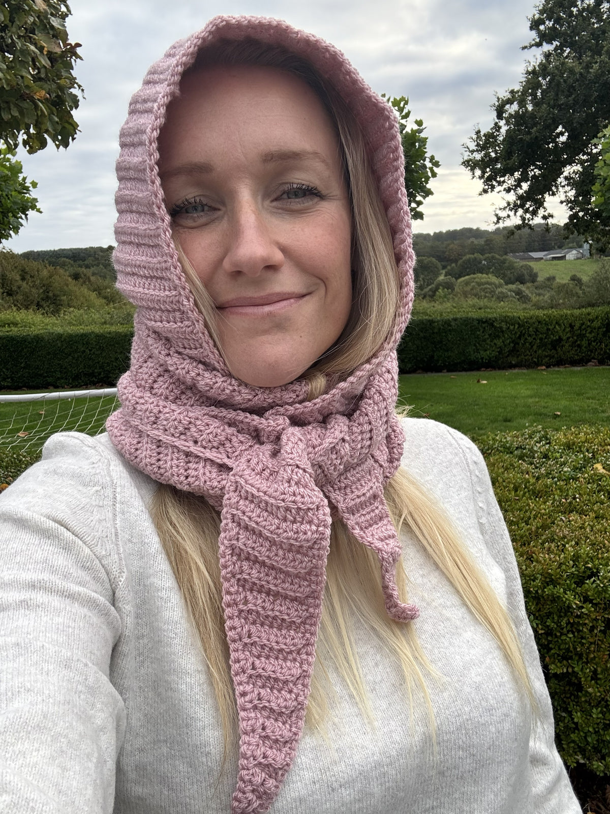 Woman wearing a pink ribbed Sophie Hood crochet scarf with tapered ends