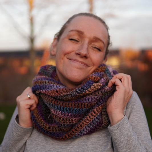 Girl wearing a crochet infinity scarf made in colorful yarn.